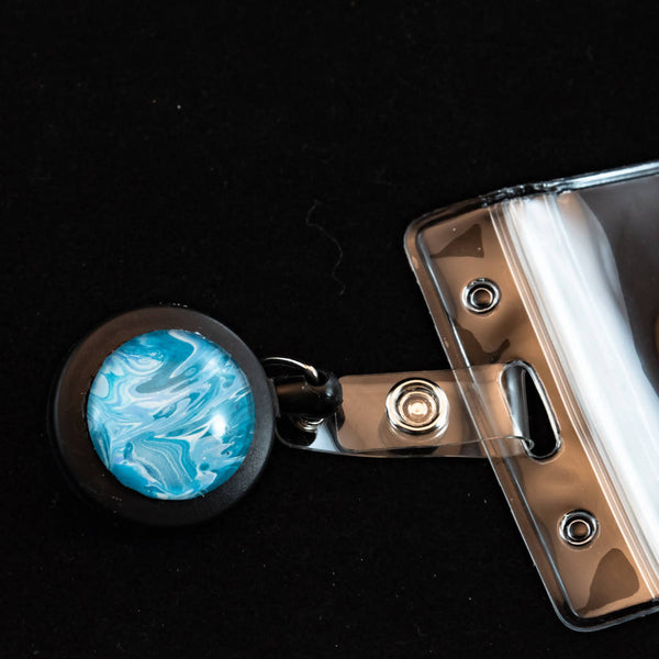 Retractable badge holder with unique acrylic painted cabochon decoration.